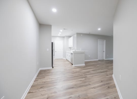 an empty living room and kitchen with white walls and wood flooring at The Lena, Raritan, NJ 08869