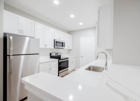 a white kitchen with stainless steel appliances and white counter tops at The Lena, Raritan, NJ 08869