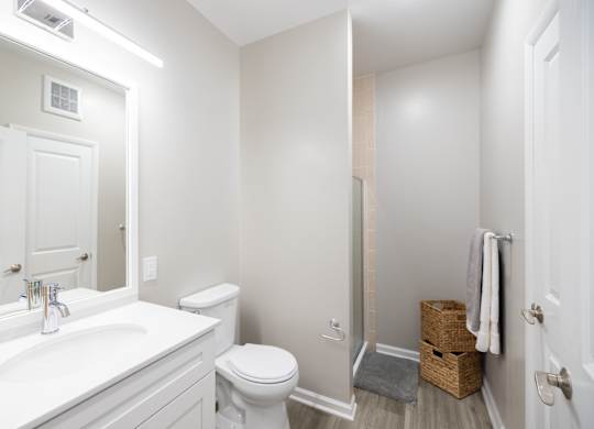 A white bathroom with a toilet, sink, and mirror at Harbor Pointe Apartments, New Jersey