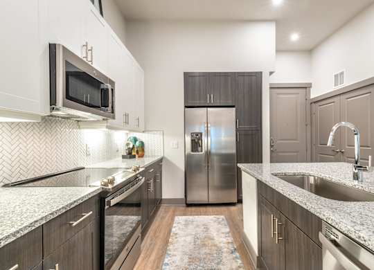 A kitchen with a refrigerator, microwave, and sink.at The Bridge at McKinney, McKinney
