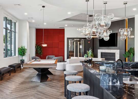 Clubhouse modern kitchen with a black countertop and a large island with a table and chairs at Metro 303, Hempstead, NY