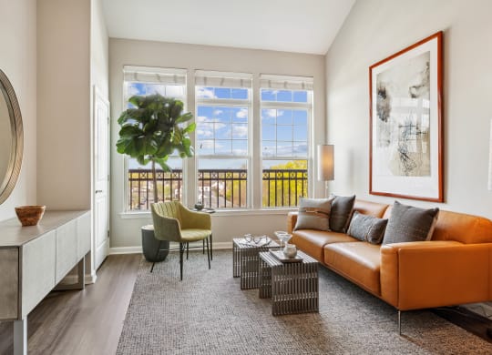a living room with a brown couch and a large plant in front of a window at Metro 303, New York, 11550