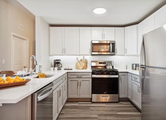 a kitchen with white cabinets and stainless steel appliances at Metro 303, Hempstead