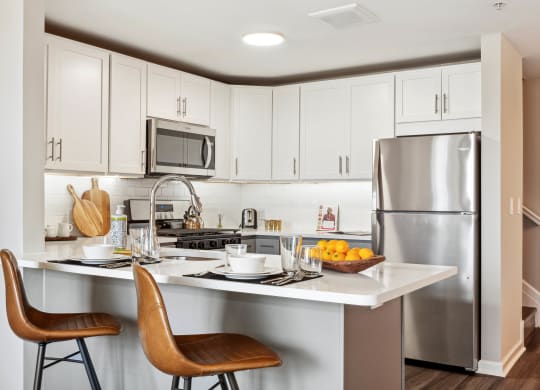 a kitchen with white cabinets and stainless steel appliances at Metro 303, Hempstead, NY
