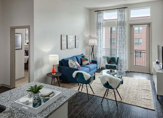A living room with a blue couch, a chair, and a table with a plant on it at Regatta Sloans Lake Apartments, Denver