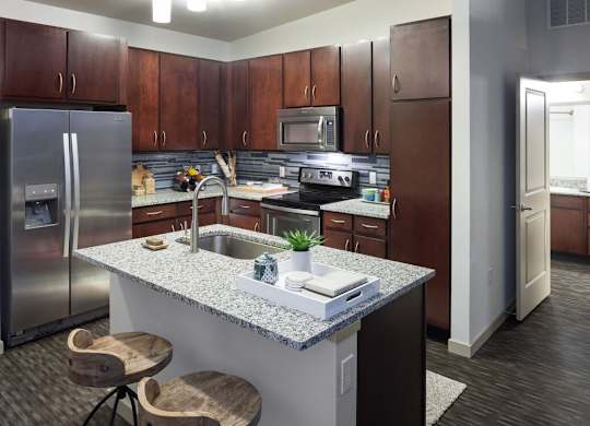 A kitchen with a granite countertop and wooden cabinets at Regatta Sloans Lake Apartments, Colorado