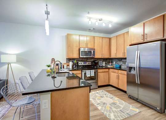 A kitchen with wooden cabinets and a black countertop at Regatta Sloans Lake Apartments, Denver, Colorado