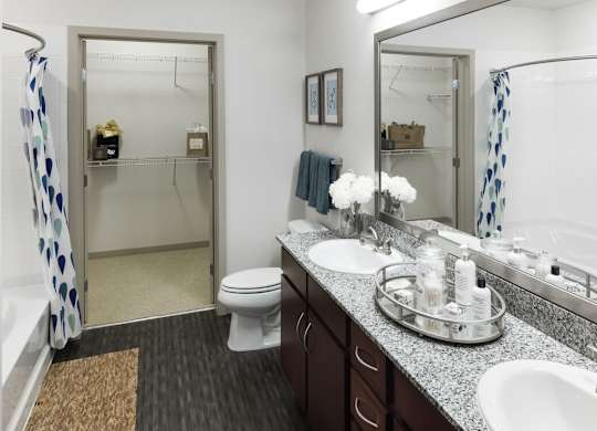 A bathroom with a toilet, sink, and mirror at Regatta Sloans Lake Apartments, Denver, CO, 80204