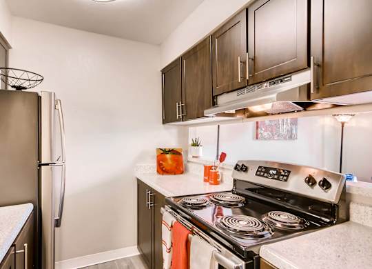 A kitchen with a stove top oven and a refrigerator at Mountain Vista Apartments, Lakewood, CO, 80228