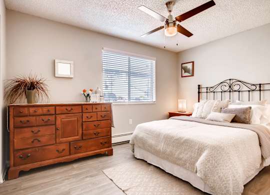 A bedroom with a bed, dresser, and ceiling fan at Mountain Vista Apartments, Lakewood, 80228