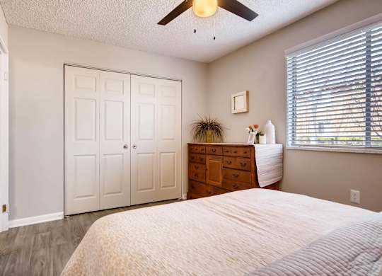 A bedroom with a bed, dresser, and a ceiling fan at Mountain Vista Apartments, Lakewood, Colorado