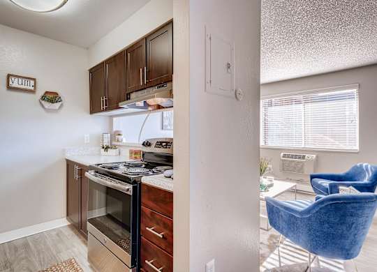 A kitchen with a refrigerator, oven, and a blue chair at Mountain Vista Apartments, Lakewood, CO