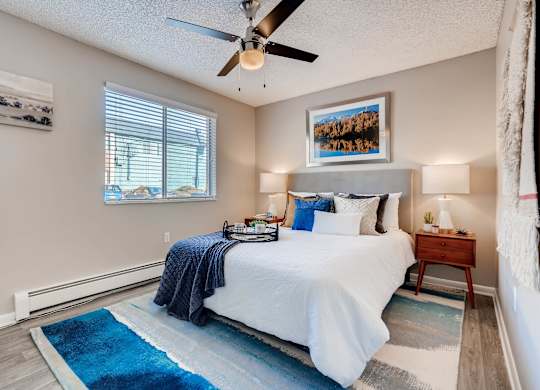 A bedroom with a bed, a ceiling fan, and a rug at Mountain Vista Apartments, Lakewood, Colorado