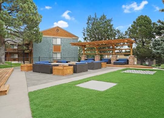A large building with a wooden pergola and a green lawn in front at Mountain Vista Apartments, Lakewood, Colorado