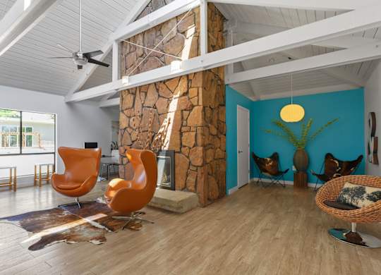 A room with a stone fireplace and wooden floors at The Ranch at Bear Creek Apartments, Lakewood, Colorado