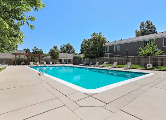 A large swimming pool surrounded by a concrete patio and lounge chairs at The Ranch at Bear Creek Apartments, Lakewood, CO, 80227