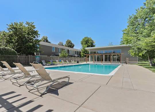 A pool with chairs around it and a building in the background at The Ranch at Bear Creek Apartments, Colorado, 80227