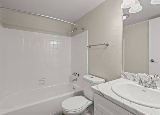 A white bathroom with a toilet, sink, and tub at The Ranch at Bear Creek Apartments, Colorado