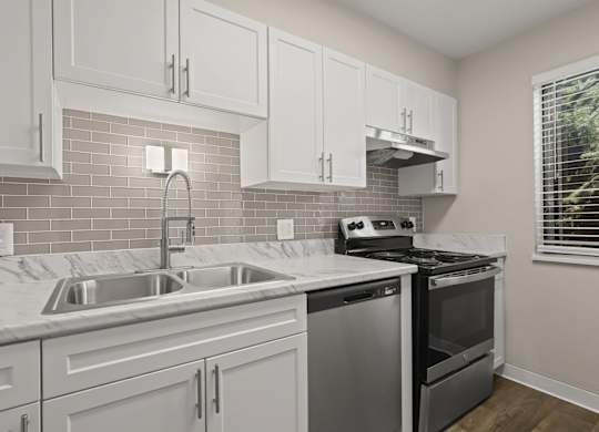 A kitchen with white cabinets and a stainless steel dishwasher at The Ranch at Bear Creek Apartments, Lakewood