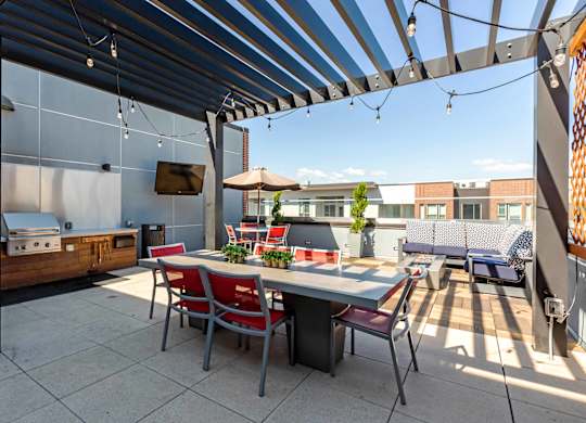 A patio with a table and chairs under a striped awning at Regatta Sloans Lake Apartments, Denver, Colorado