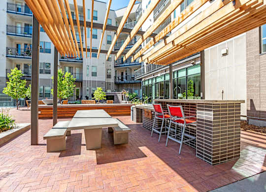 A patio with a table and chairs under a wooden canopy at Regatta Sloans Lake Apartments, Denver, CO