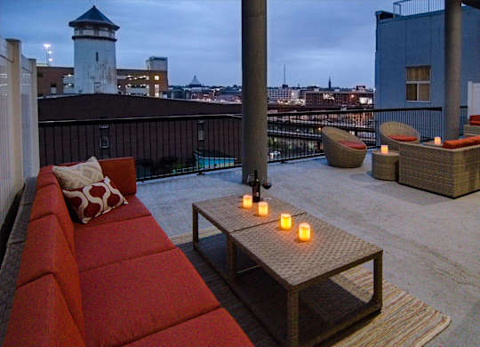 A balcony with a red couch and candles on a table.
