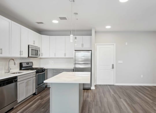a kitchen with white cabinets and stainless steel appliances at Metro 303, Hempstead New York