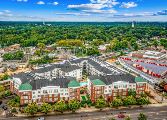 an aerial view of a large building complex with trees in the background and a blue sky with at West 130, West Hempstead, NY