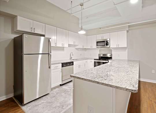 A kitchen with a granite counter top and stainless steel appliances.