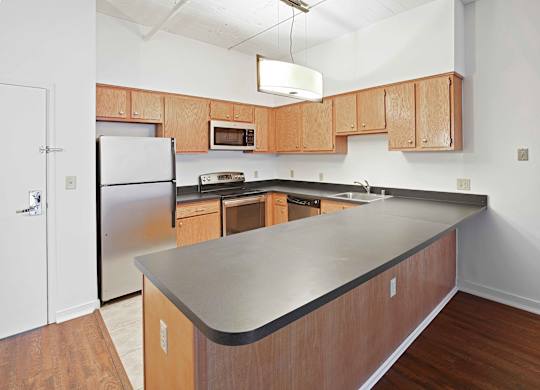 A kitchen with wooden cabinets and a black counter top.