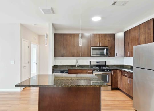a kitchen with dark wood cabinets and an island with granite countertops at West 130, New York