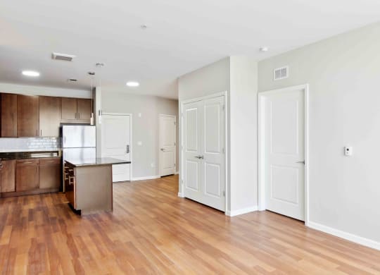 an empty living room with a kitchen in the background at West 130, West Hempstead, NY 11552