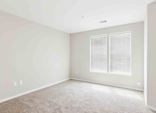 a bedroom with white walls and a window with white shutters at West 130, West Hempstead
