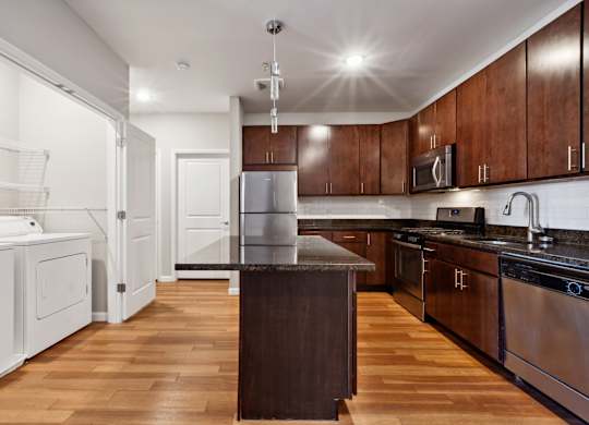 Kitchen with wooden floors and stainless steel appliances at West 130, West Hempstead