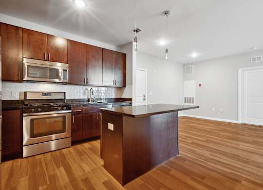 Living room and kitchen with wood flooring and cabinets at West 130, West Hempstead, NY