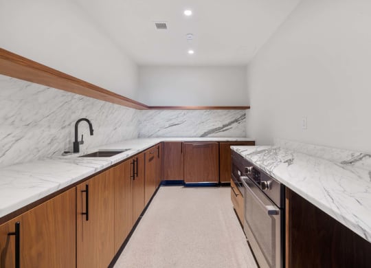 the kitchen has marble counter tops and wooden cabinets and stainless steel appliances at The Paxton, Brooklyn, NY 11201