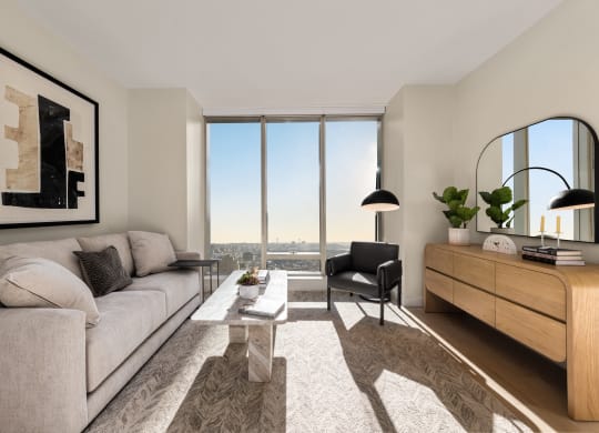 a living room with a large window and a couch and a table at The Paxton, Brooklyn, 11201