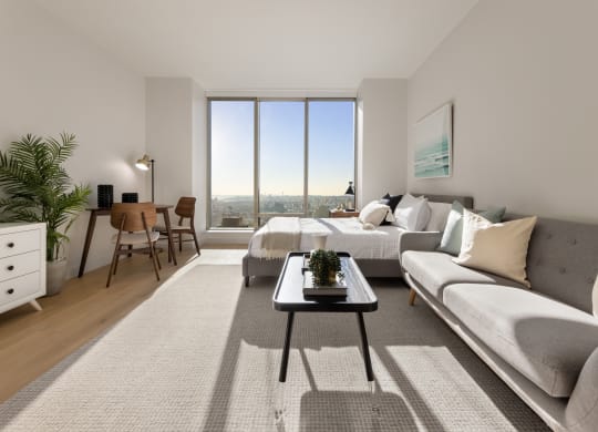 a living room with a couch and a table and a large window at The Paxton, Brooklyn, 11201