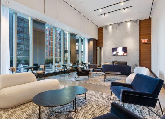 a lounge area with couches chairs and tables and a television at The Paxton, Brooklyn, NY