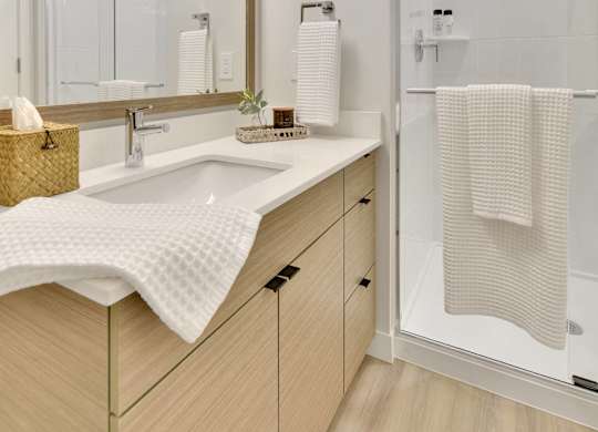 A bathroom with a sink, mirror, and shower.