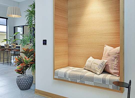 A modern room with a wooden panelled wall and a bench with cushions.