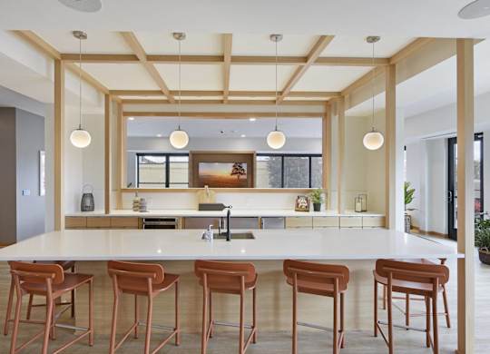 A kitchen with a white counter and brown stools.