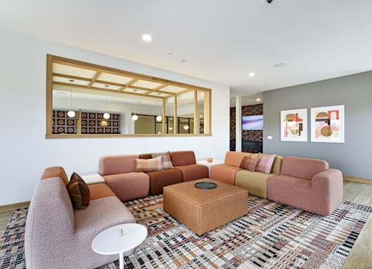 A living room with a pink couch, a white table, and a large mirror on the wall.