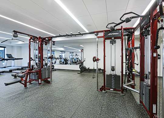 A gym with a variety of equipment including a weight bench and a leg press machine.