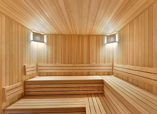 A wooden sauna with benches and lights on the wall.