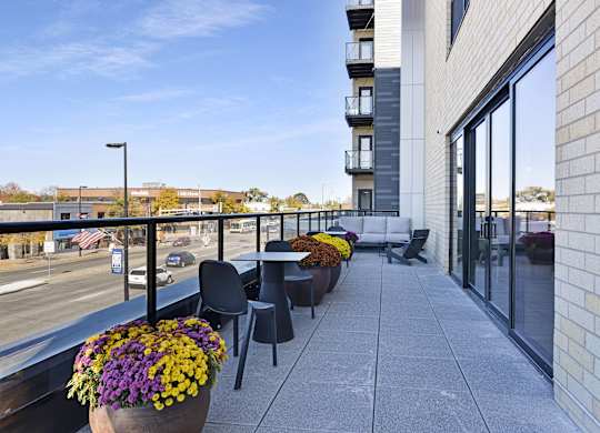 A balcony with a table and chairs overlooking a street.