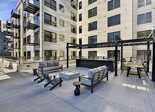 A patio area with a table and chairs is surrounded by apartment buildings.