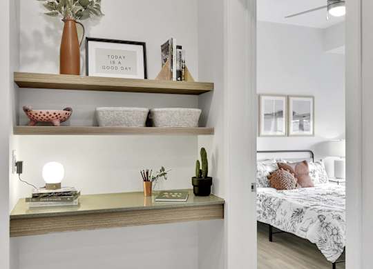 A bedroom with a bed, a shelf with decorative items, and a mirror.