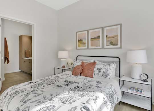 A bedroom with a large bed and a nightstand with a lamp on it.