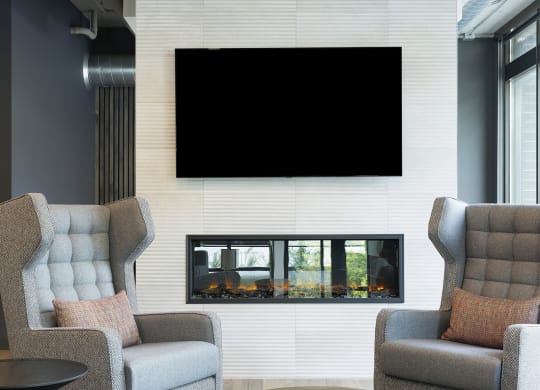 a living room with two chairs and a television on the wall